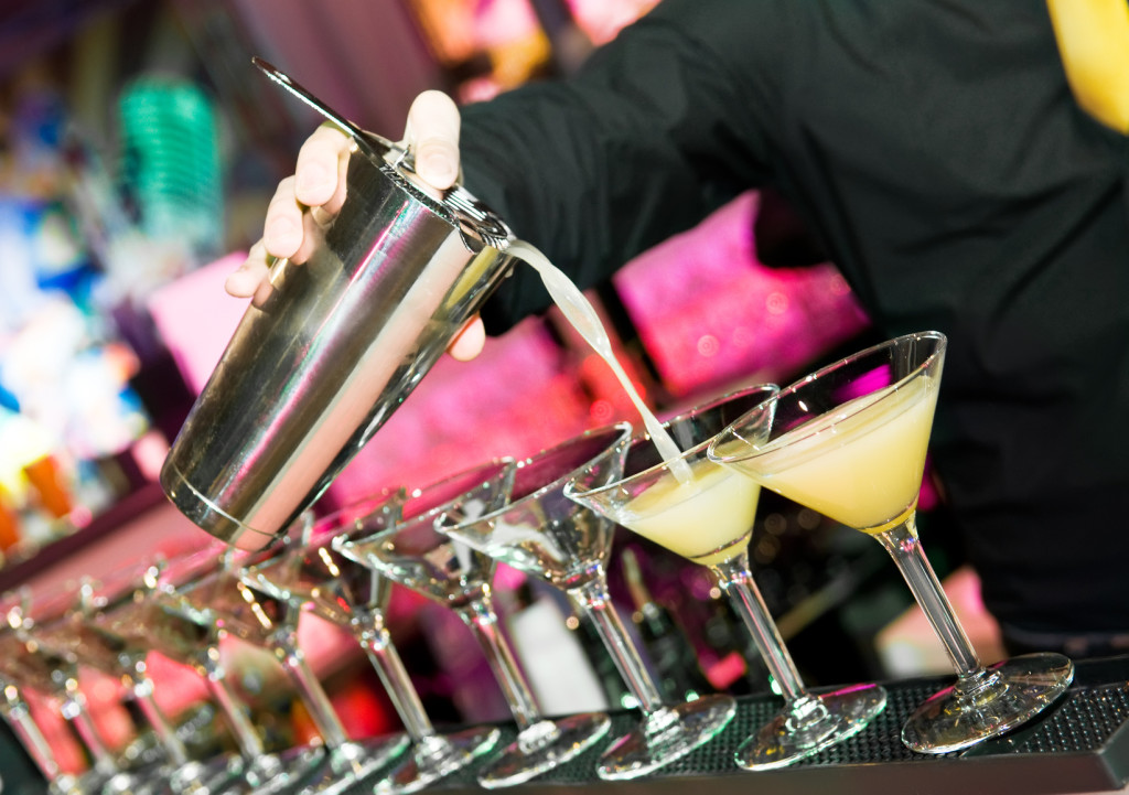 barman’s hand with shaker and cocktails