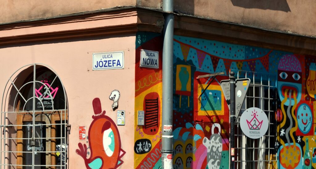 Narożnik ulic Józefa i Nowej na krakowskim Kazimierzu z kolorowym muralem na ścianie kamienicy