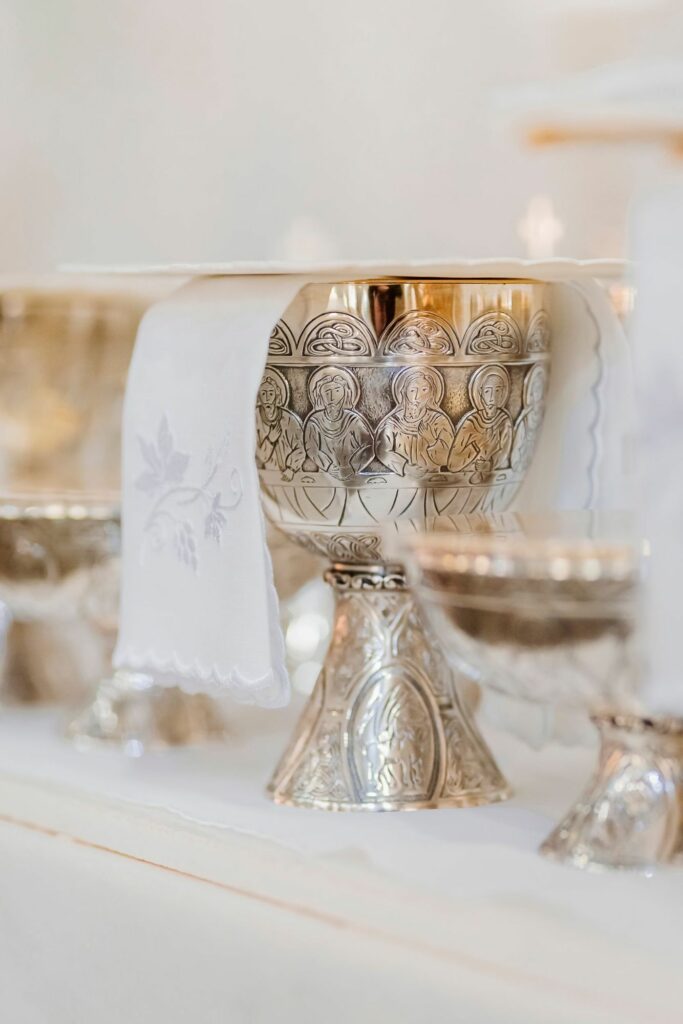 Silver chalice with a Last Supper motif on an altar covered with white linen