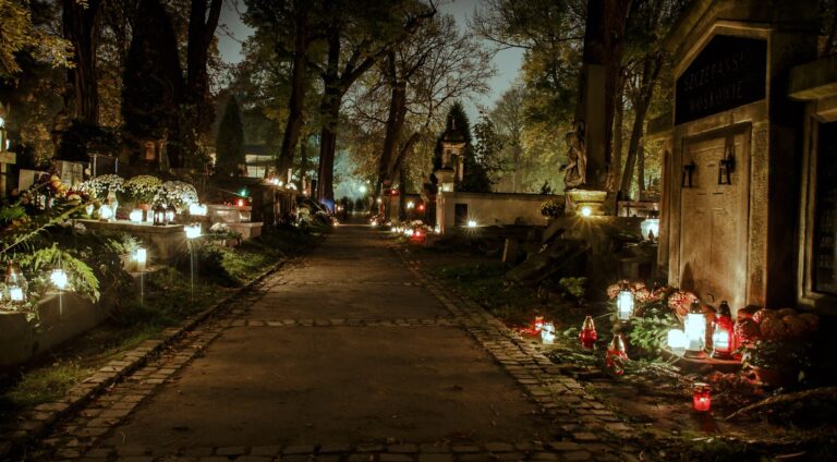 Allee des Rakowicki-Friedhofs in Krakau an Allerheiligen bei Nacht, Gräber im Licht von Grabkerzen